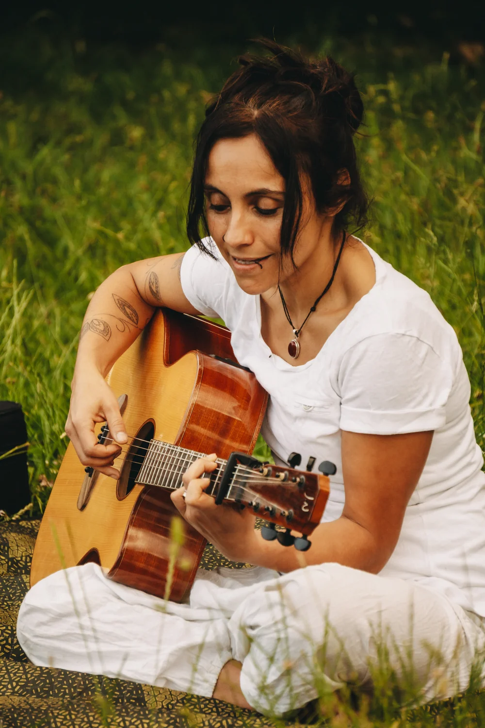 Dani spielt Gitarre auf einer Wiese zur Begleitung von Mantras